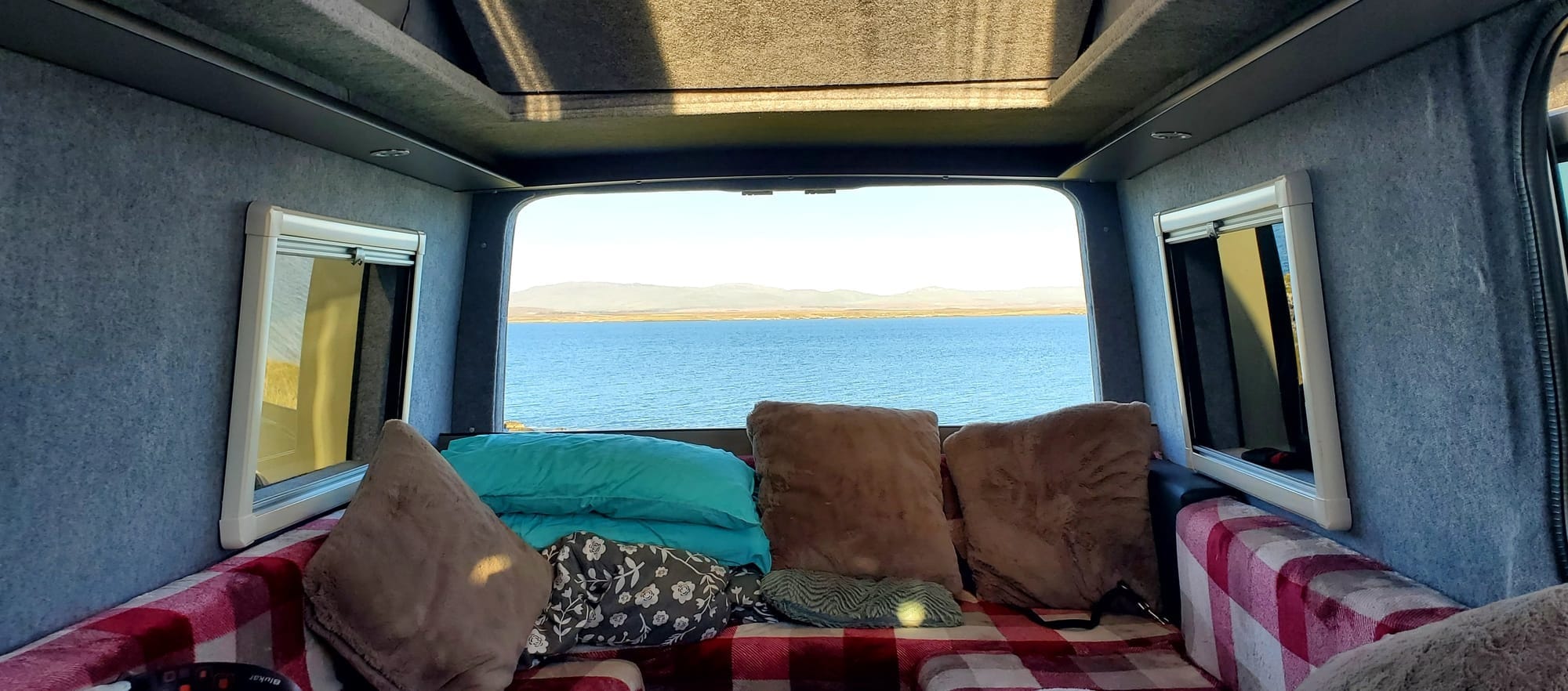 A view across the water to distant hills taken from inside the campervan.