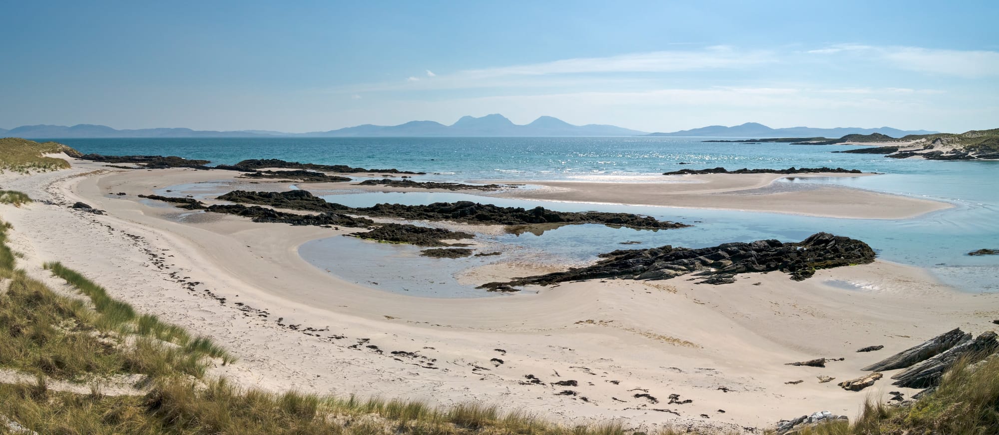 The Paps of Jura on the horizon seen from a white sandy beach on the isle of Colonsay.