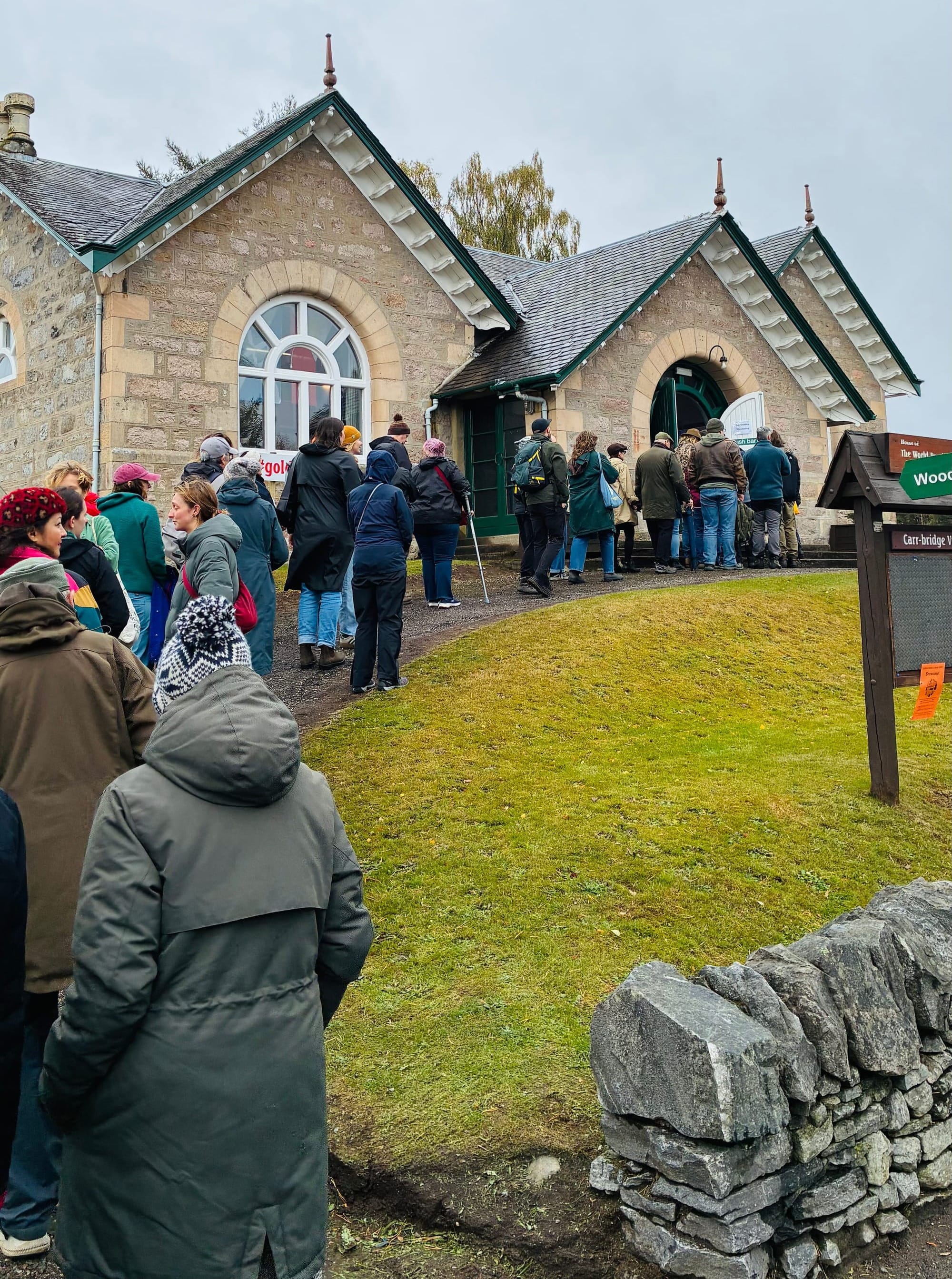 A queue of people leading up the gravel path to the village hall.