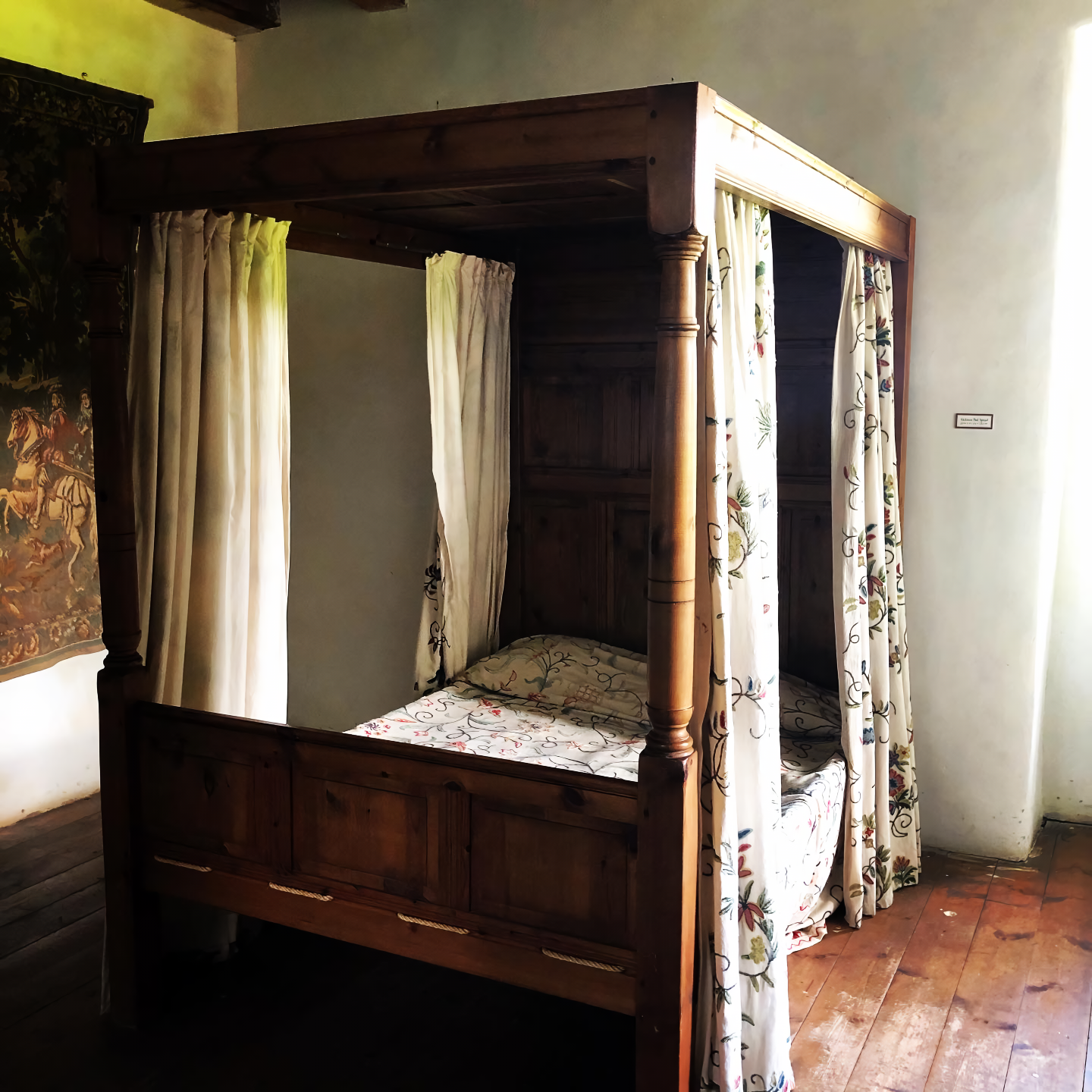 A four-poster bed in the castle. There are wooden floors and white walls. 