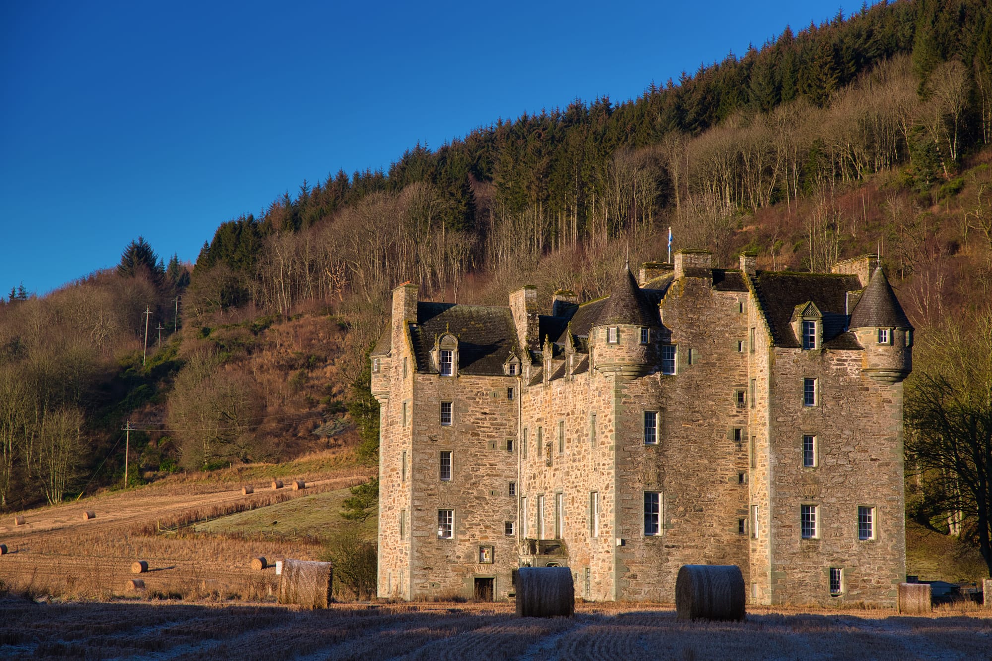 Castle Menzies in daytime, with a blue sky behind it.