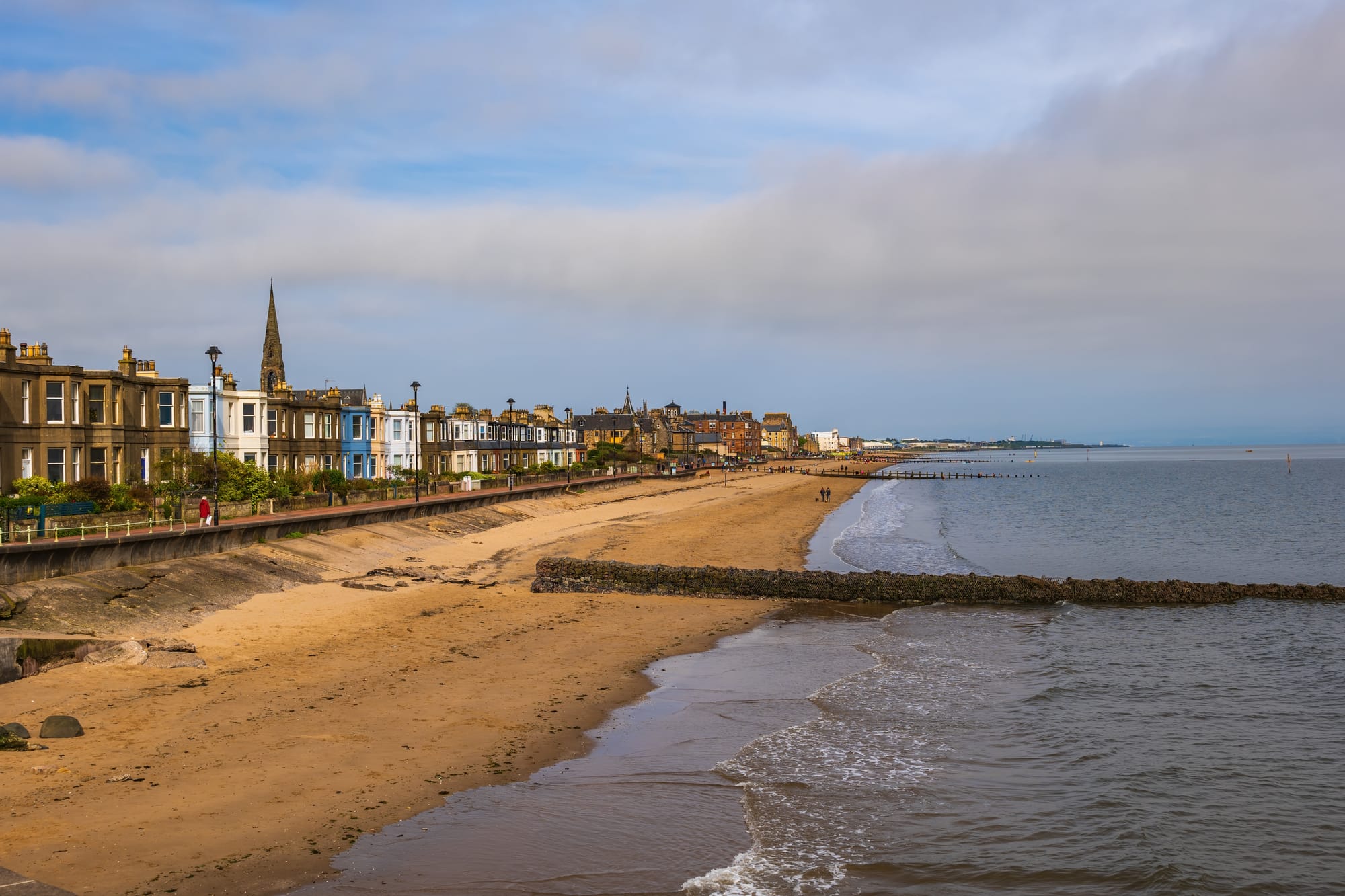 Portobello beach has a sandy stretch and houses. The sky is cloudy.