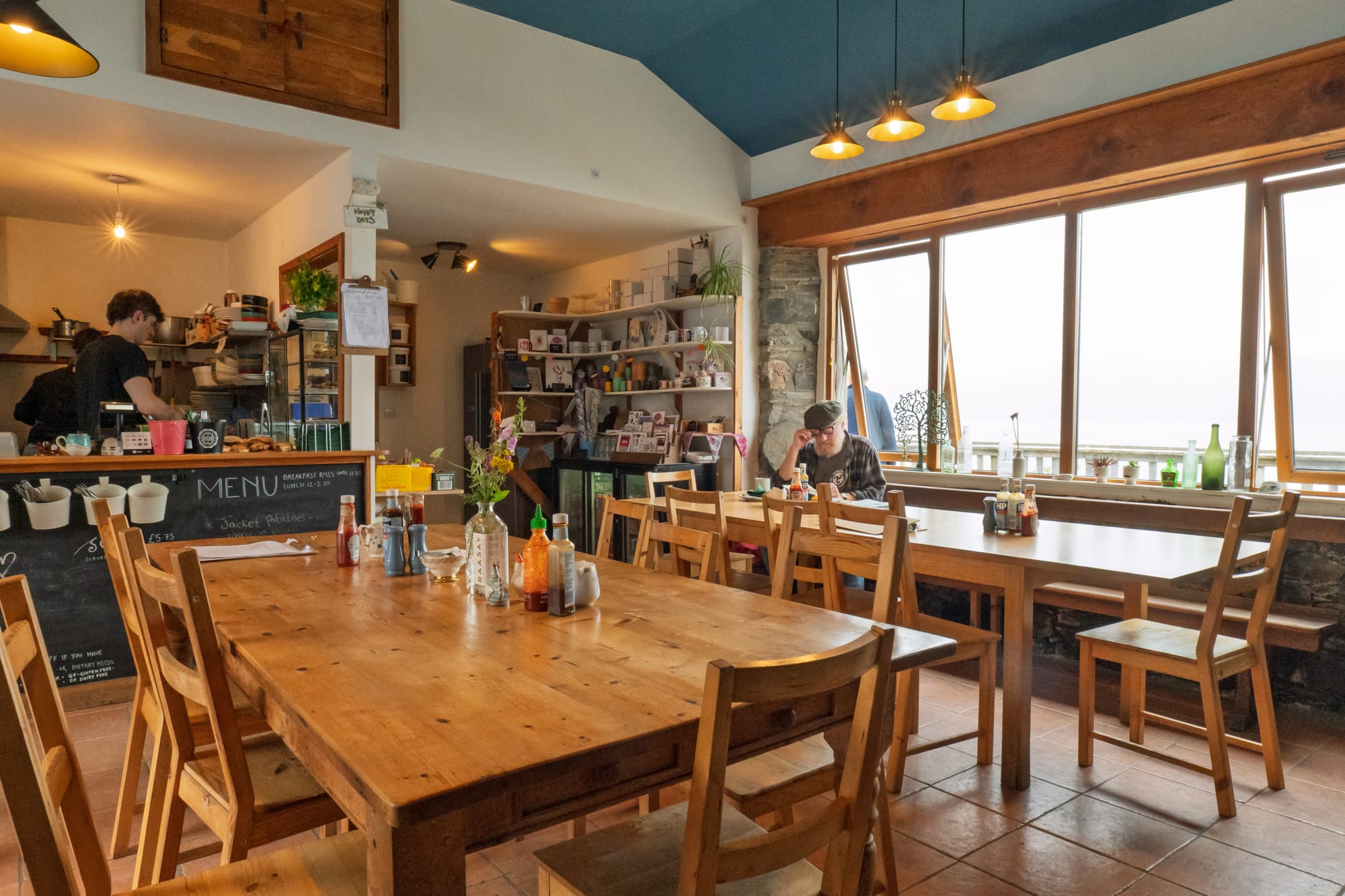 Large wooden tables in the Pottery and Tearoom, with a café bar in the background.