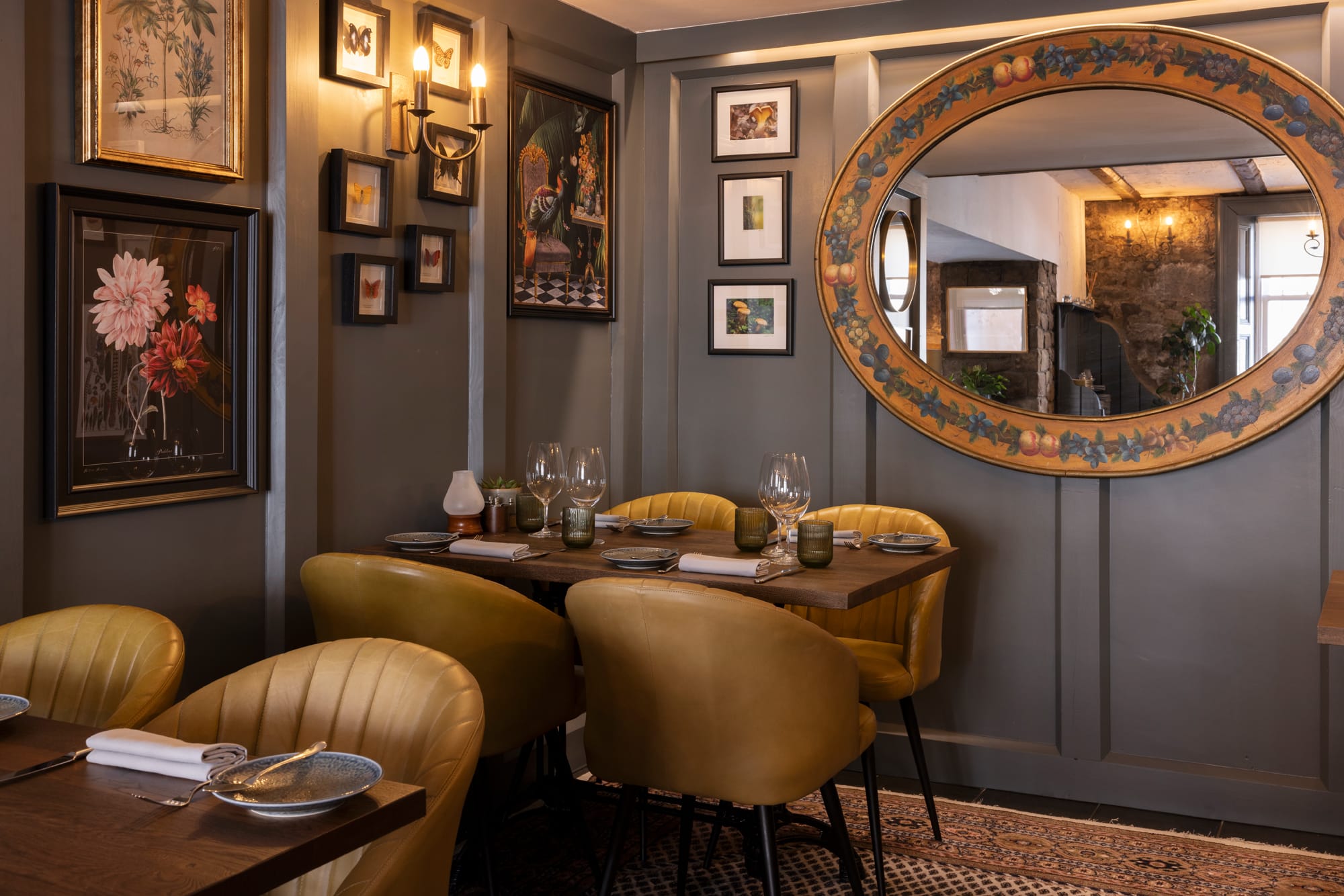 Mustard yellow chairs at wooden tables in the dining area. The walls are painted grey and there is a large mirror on the wall.
