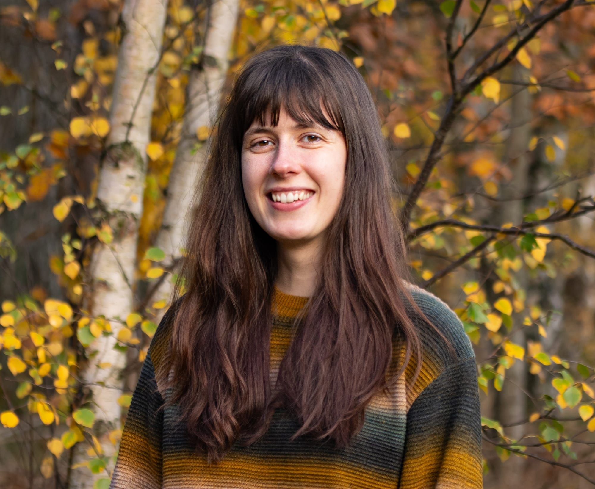 Rebecca standing in front of a tree with yellow leaves.