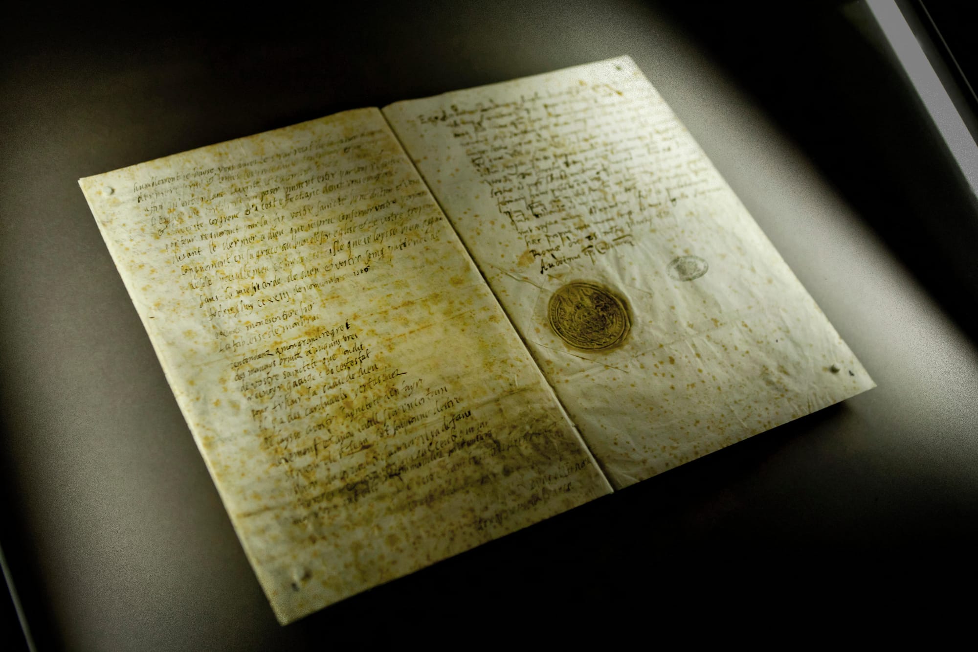 A historic letter sits on a dark background. The pages are yellowed and the handwriting is in brown ink.
