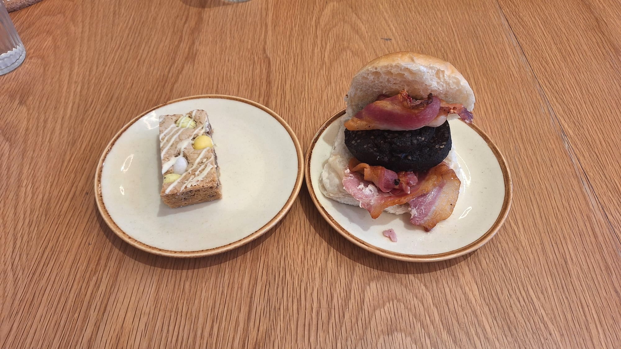 Left: a slice of mini egg traybake. Right: a very full bacon and black pudding roll.