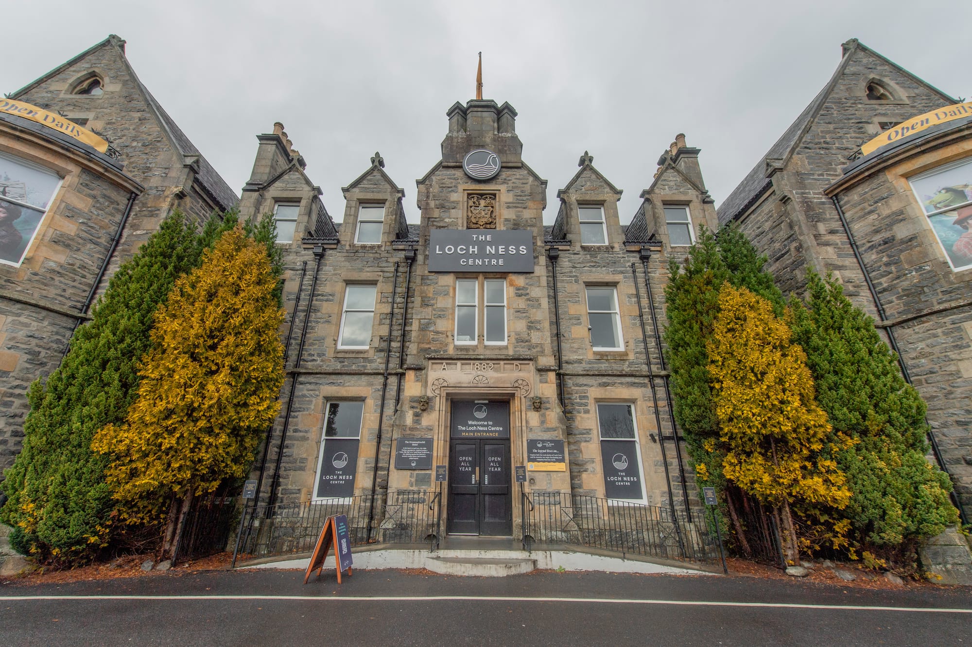 The Loch Ness Centre - a large stone building with trees at either side of the black doors.