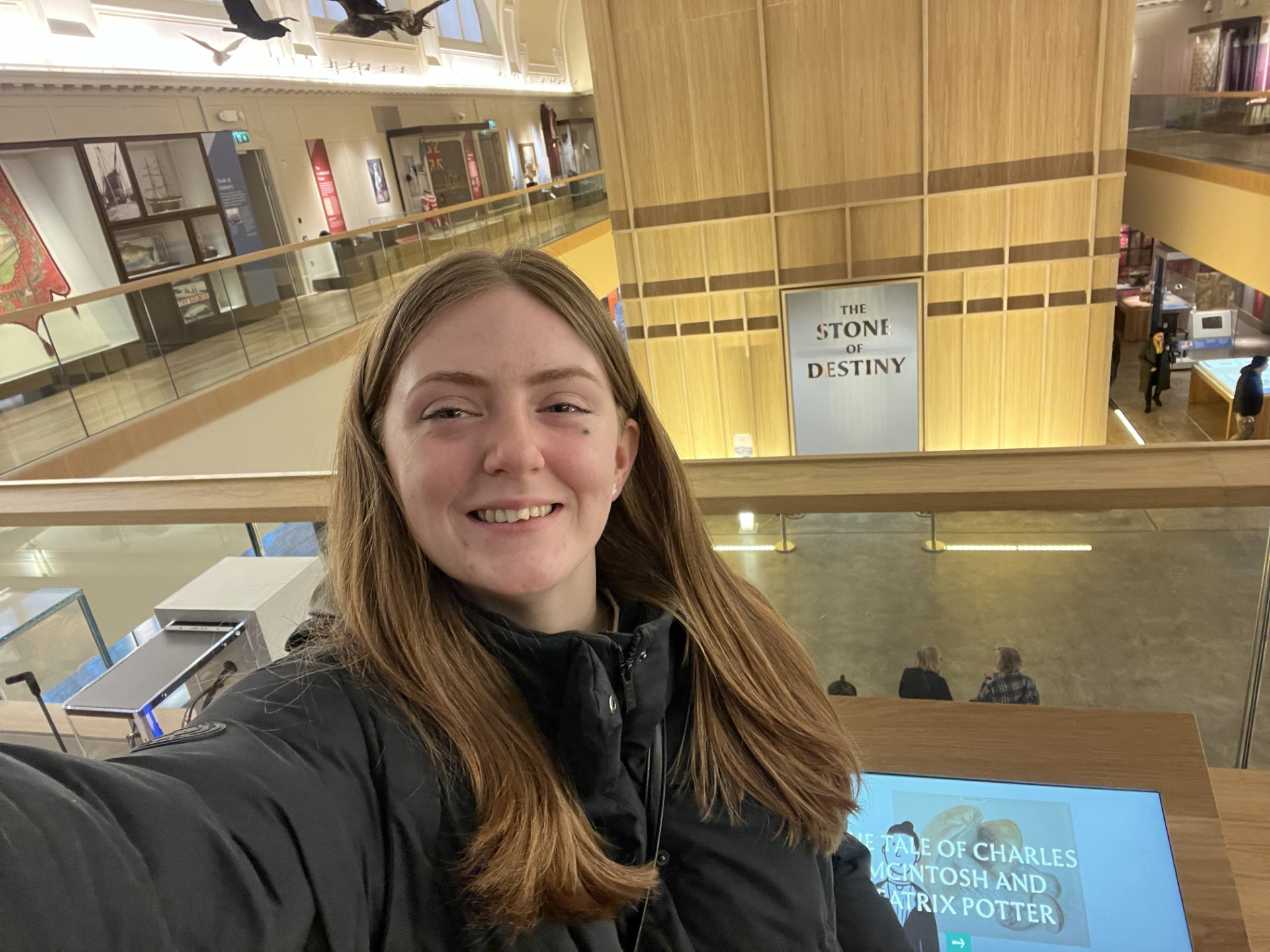 Beth smiles for a selfie with the Stone of Destiny Experience room in the background.
