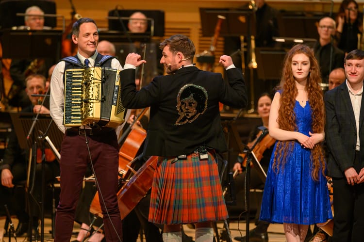Ally Heather with his back to the audience on the BBC's Burns Night programme pointing to a sequined image of Burns on the back of his jacket.